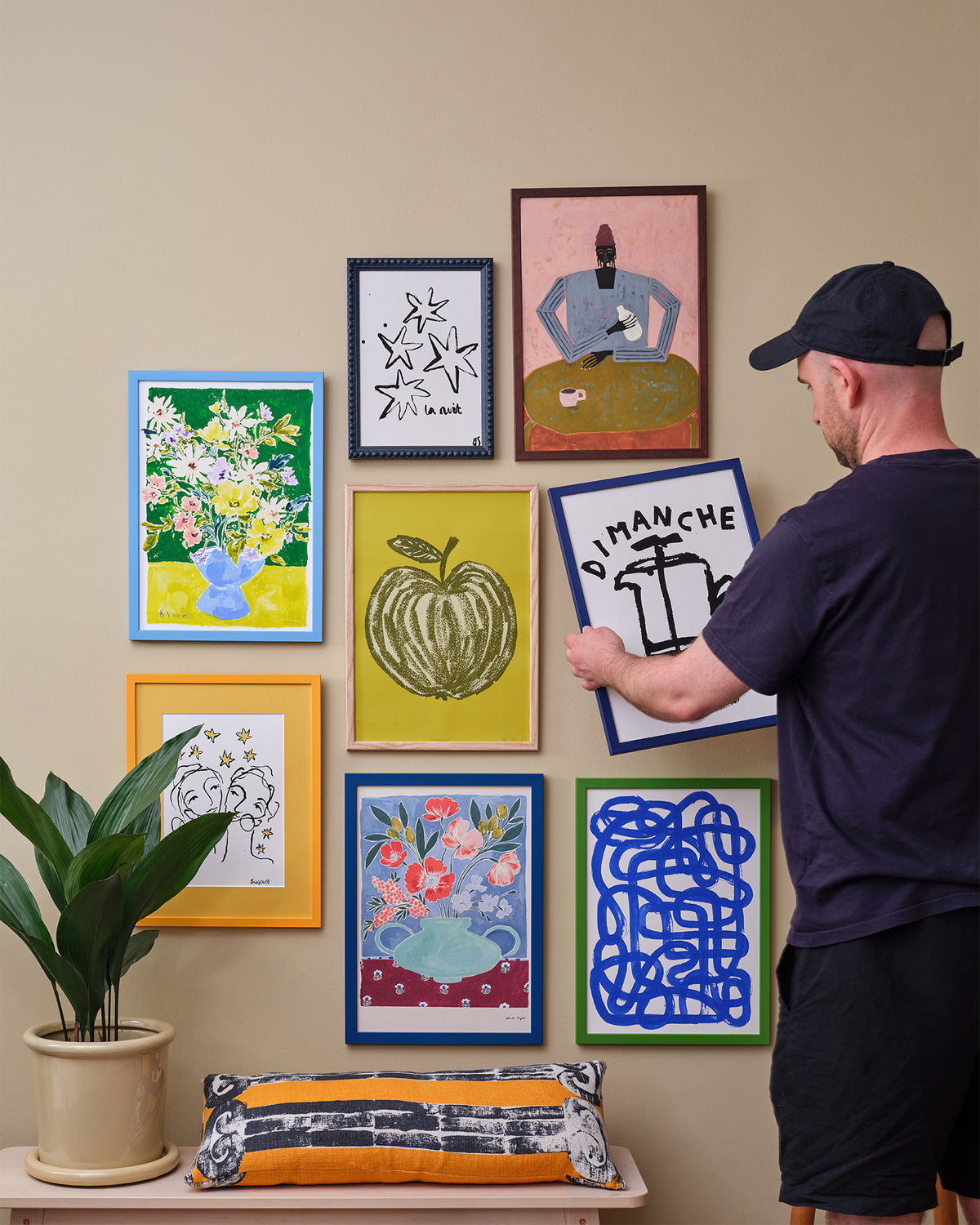 Person hanging a navy slim frame with a black-and-white print on a gallery wall